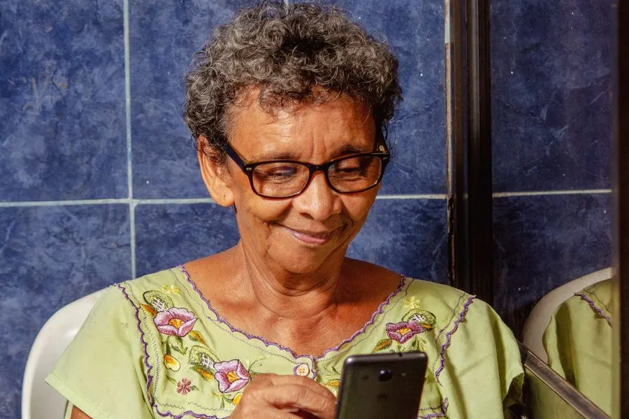 A smiling older woman uses her smartphone.