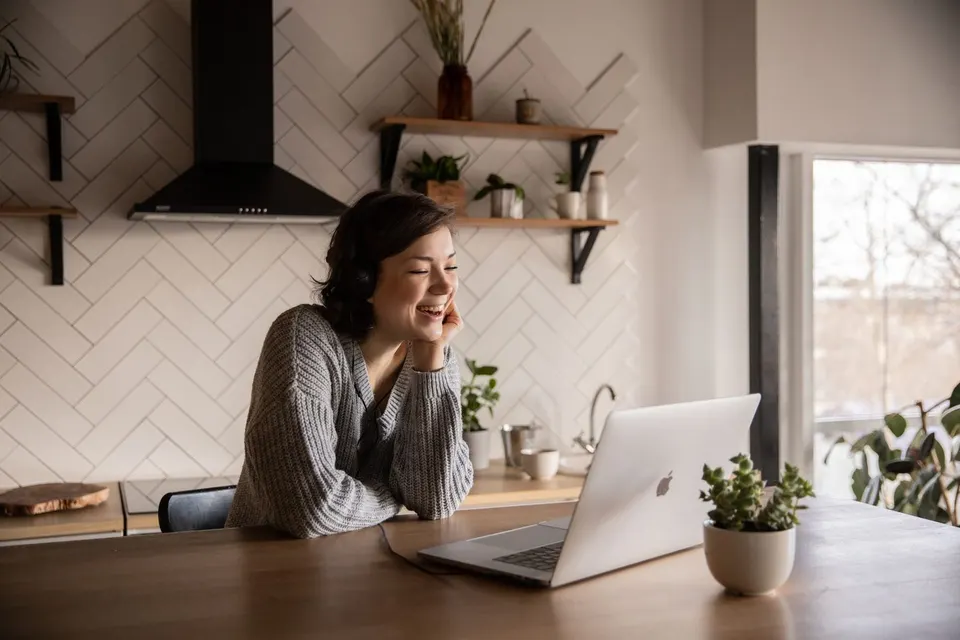 A woman smiles during a video call on her laptop.